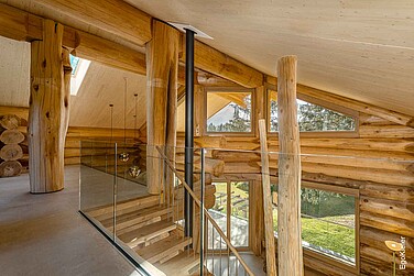 Vista interna del piano superiore della casa di legno di Amden/SG, con diverse finestre in legno EgoWoodstar e un'elegante porta scorrevole a sollevamento in legno, perfettamente integrata nel concetto architettonico generale.