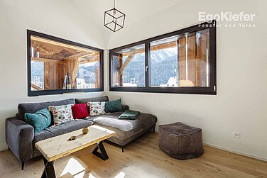 Appartement de vacances « Chasa Pütvia », photo de l'intérieur avec une fenêtre à vitrage fixe et une fenêtre en bois/aluminium à 2 vantaux en noir