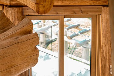 Vista interna della casa in legno massiccio con porta scorrevole in legno nella foto, che si integra armoniosamente nell'architettura naturale in legno e offre una vista sulla terrazza.