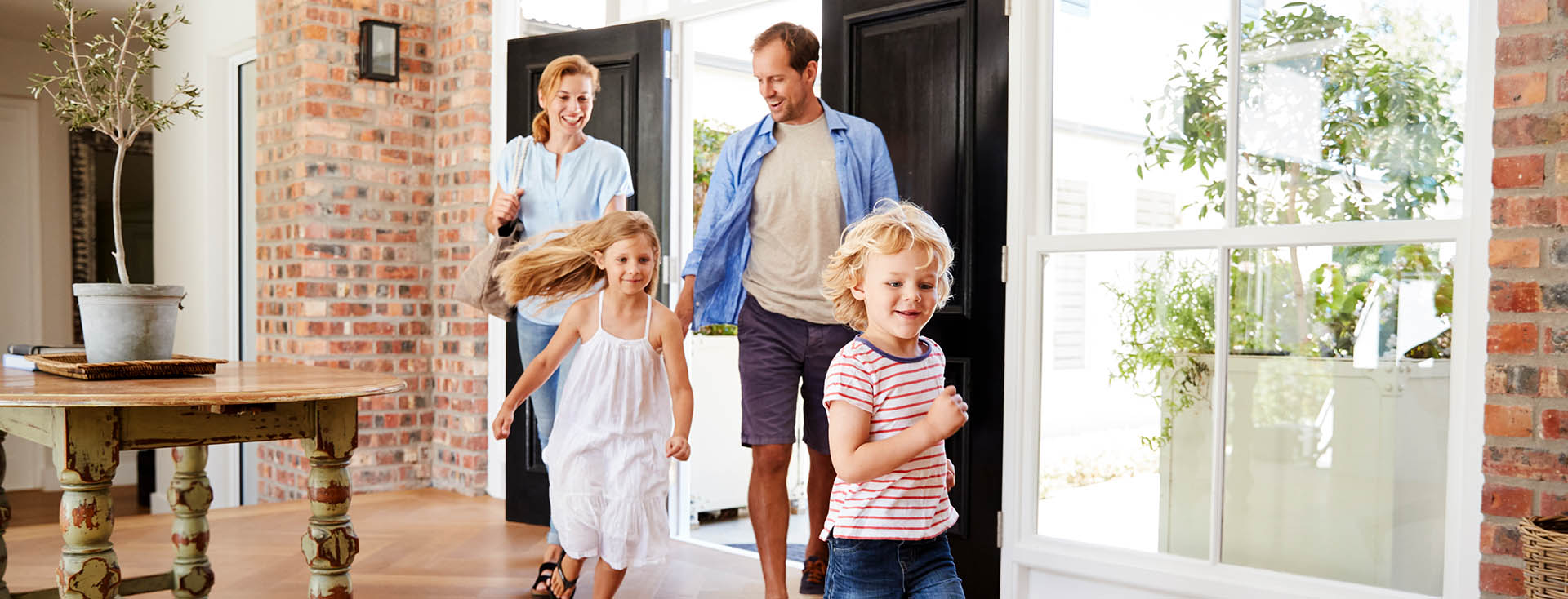 Famille entrant dans un salon lumineux par une porte ouverte